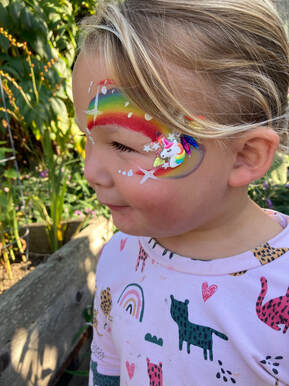 Bay Area child with rainbow face paint and unicorn jewel